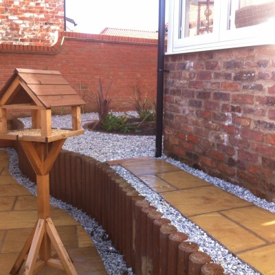 Raised patio using wooden poles, gravel and planting area