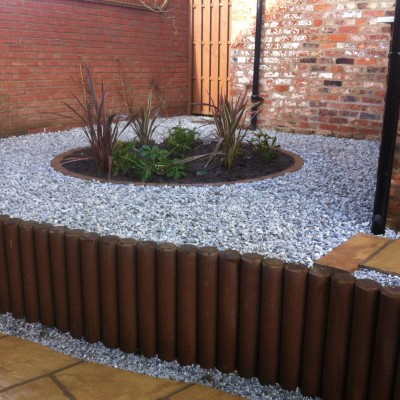 Raised patio using wooden poles, gravel and planting area